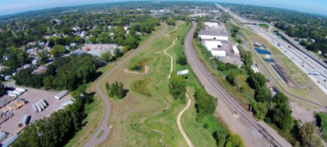 Fisheye aerial view depicts park bordered by freeway, development